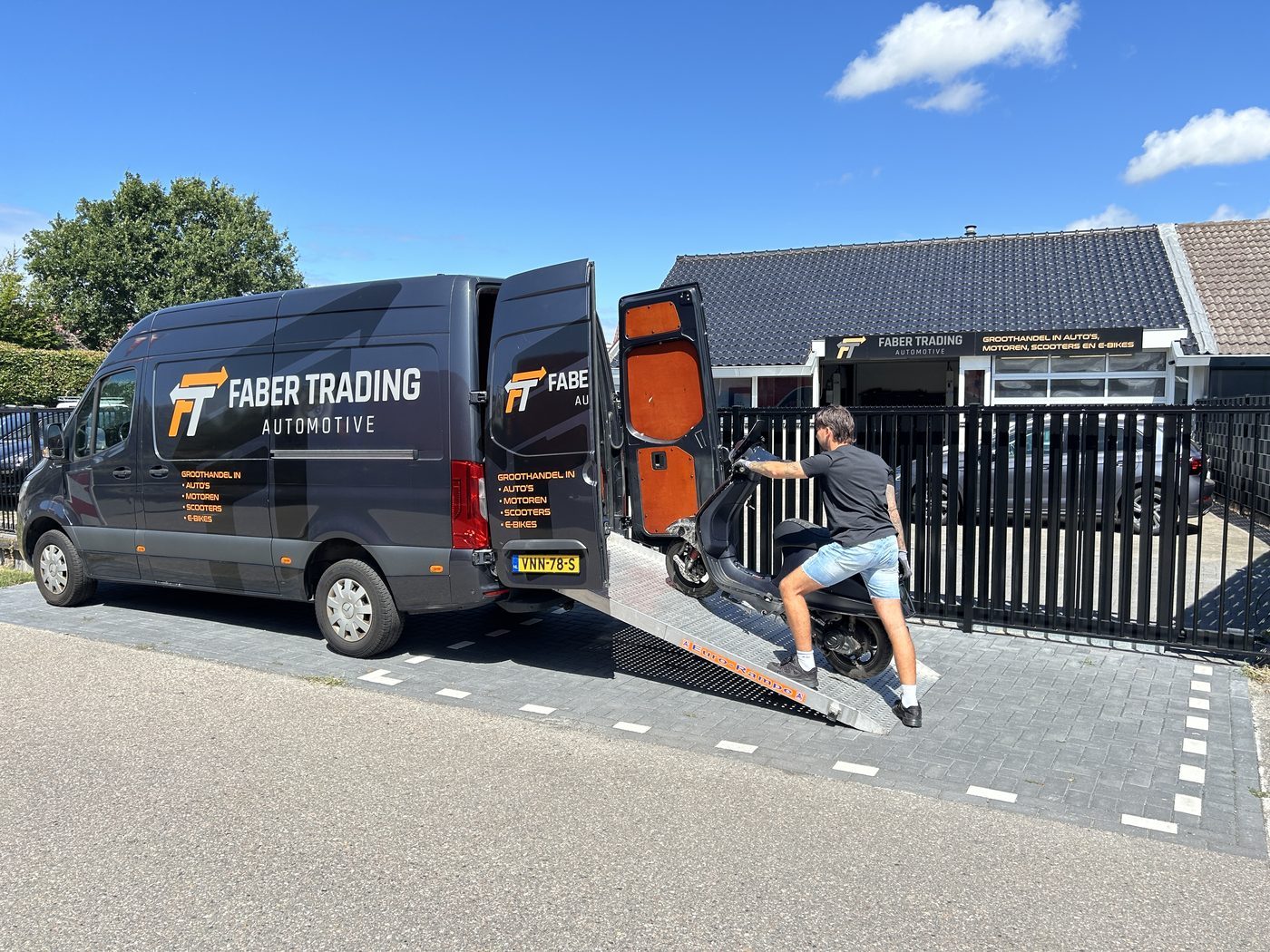 Onze bus met oprijplaat voor de deur; een scooter wordt ingeladen