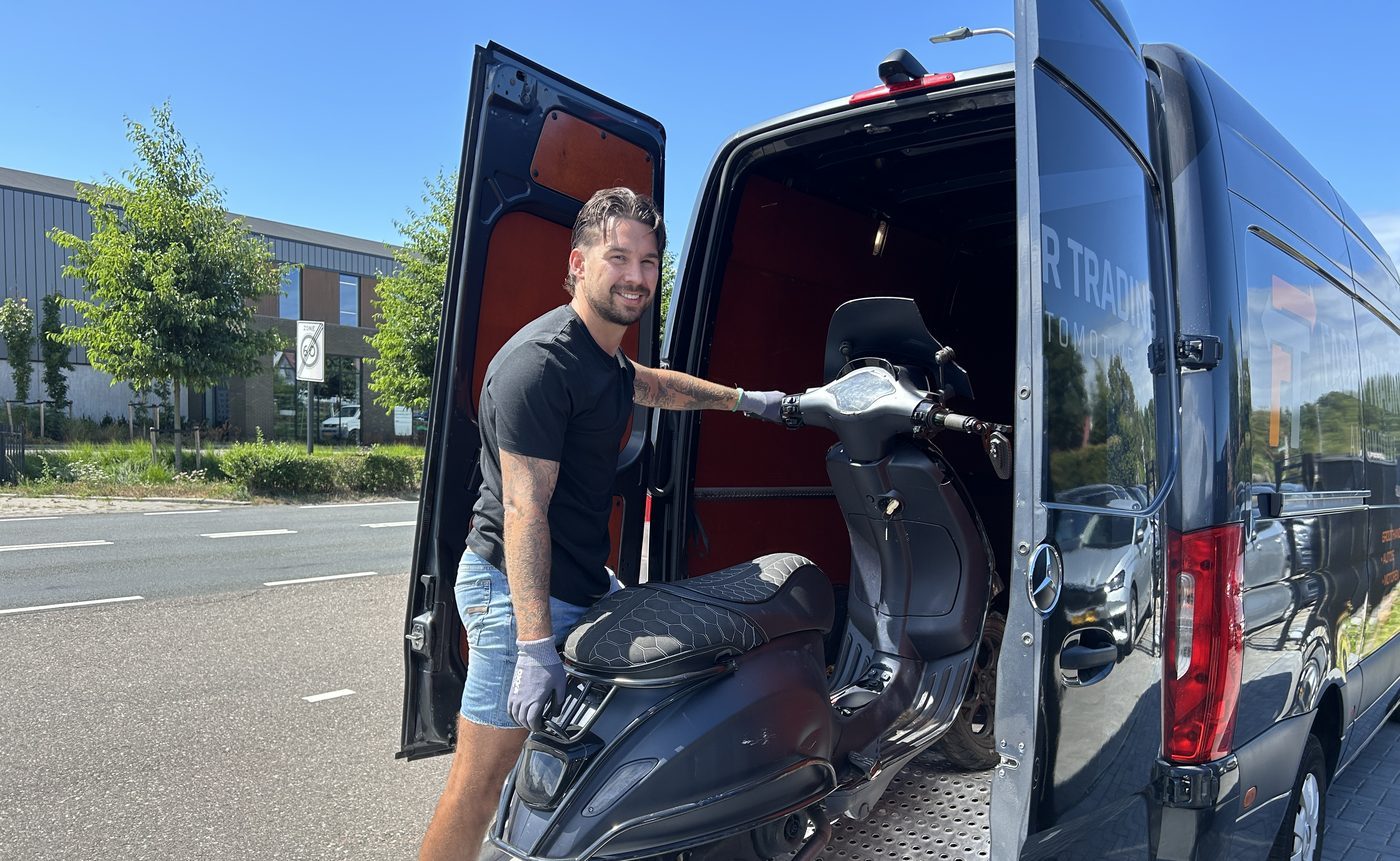 Een scooter wordt in onze bus geladen voor transport naar de werkplaats
